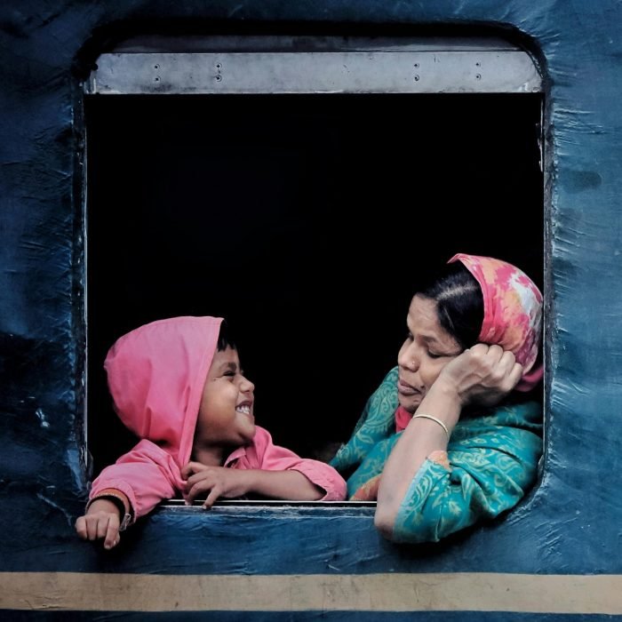 A touching moment of a mother and child sharing smiles through a train window, capturing warmth and connection.